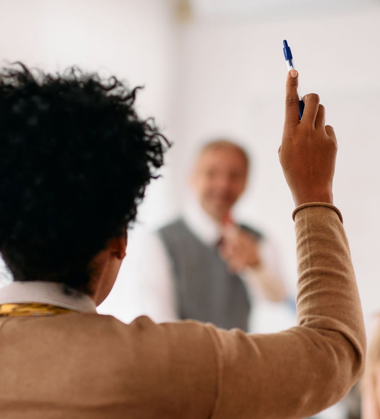 A student raising their hand in a classroom.