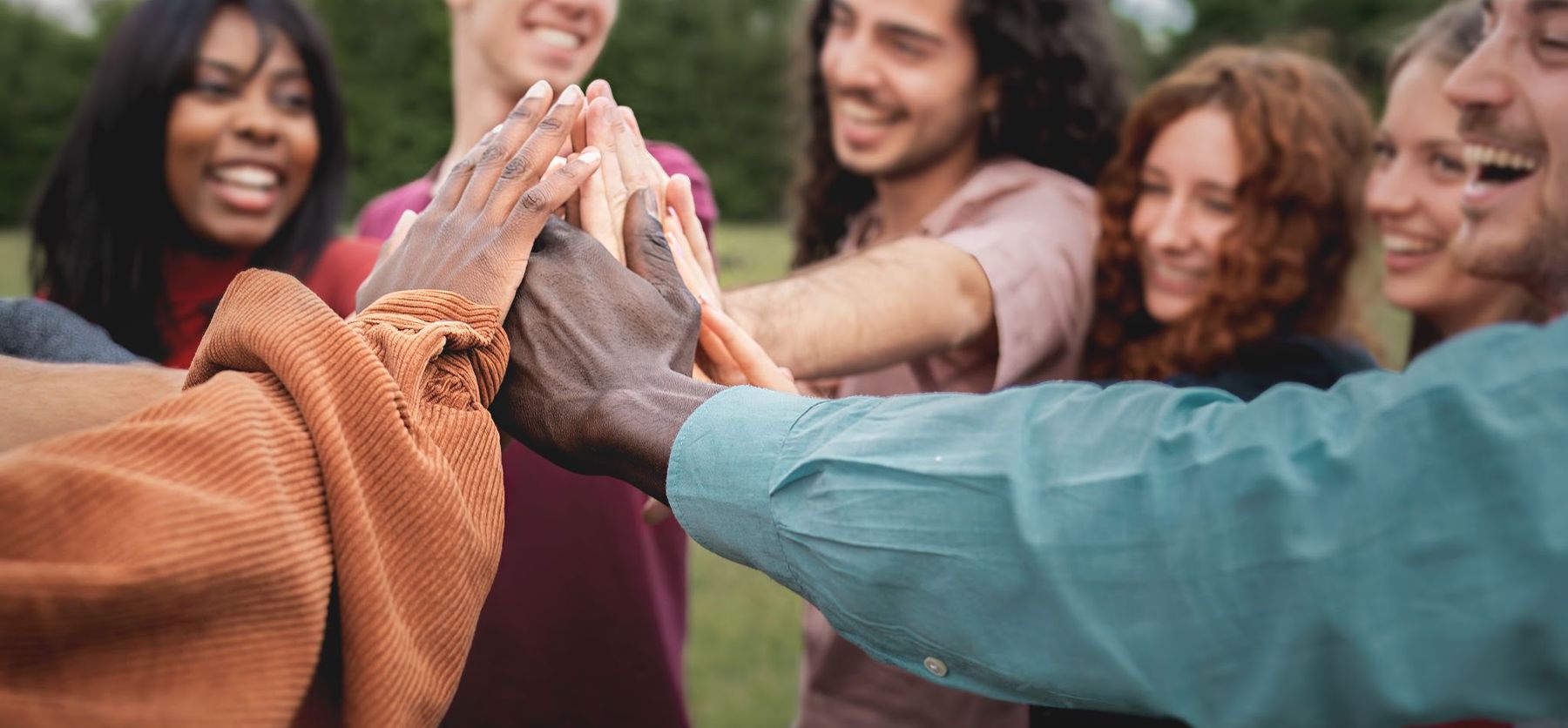 Several people putting their hands together in the centre of a circle.