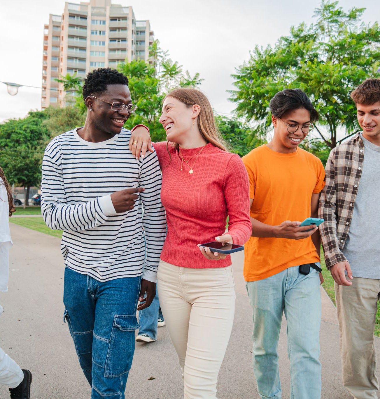 A group of young adults walking together along a tree-lined street.